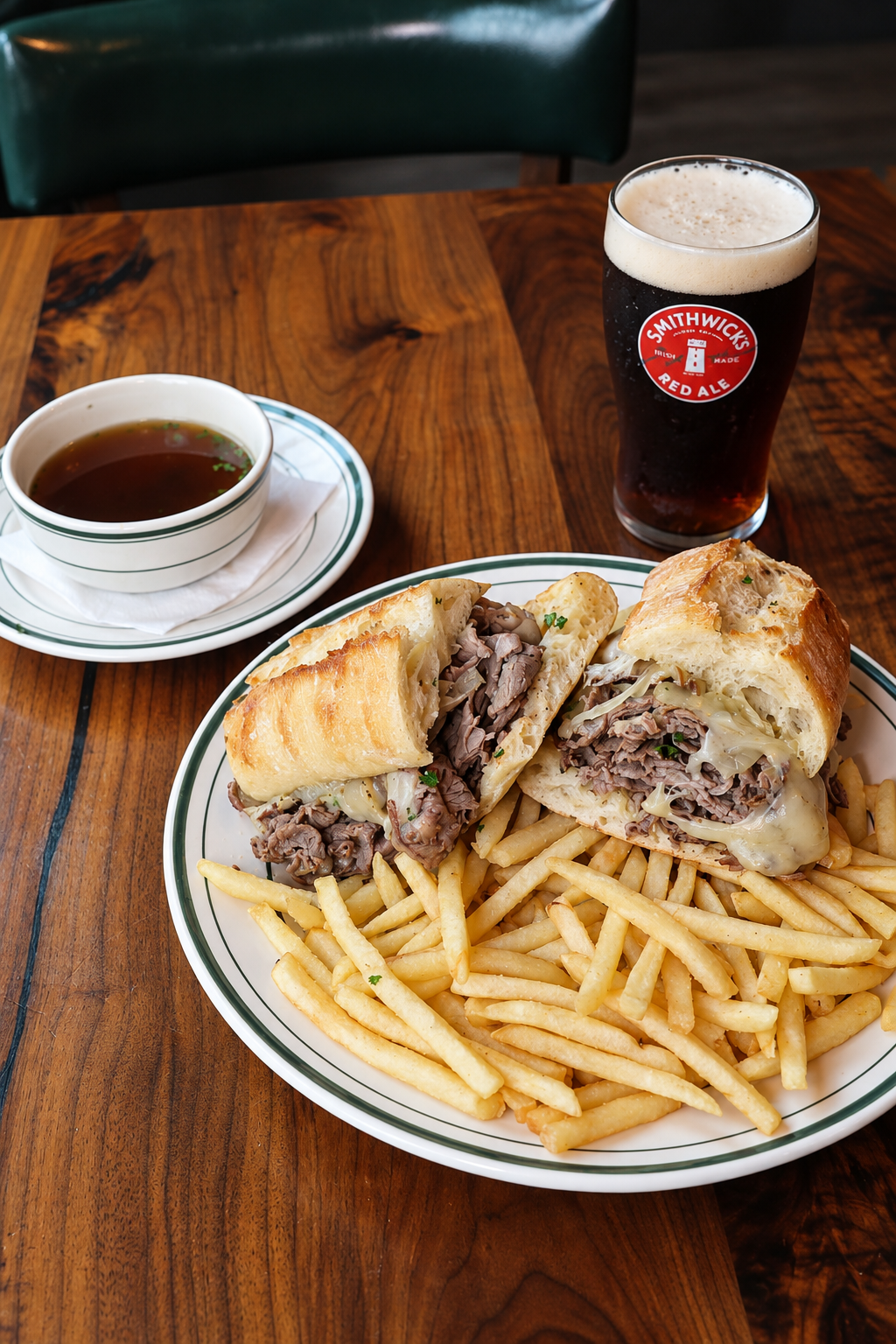 French dip sandwich with fries, au jus, and a Smithwick's red ale