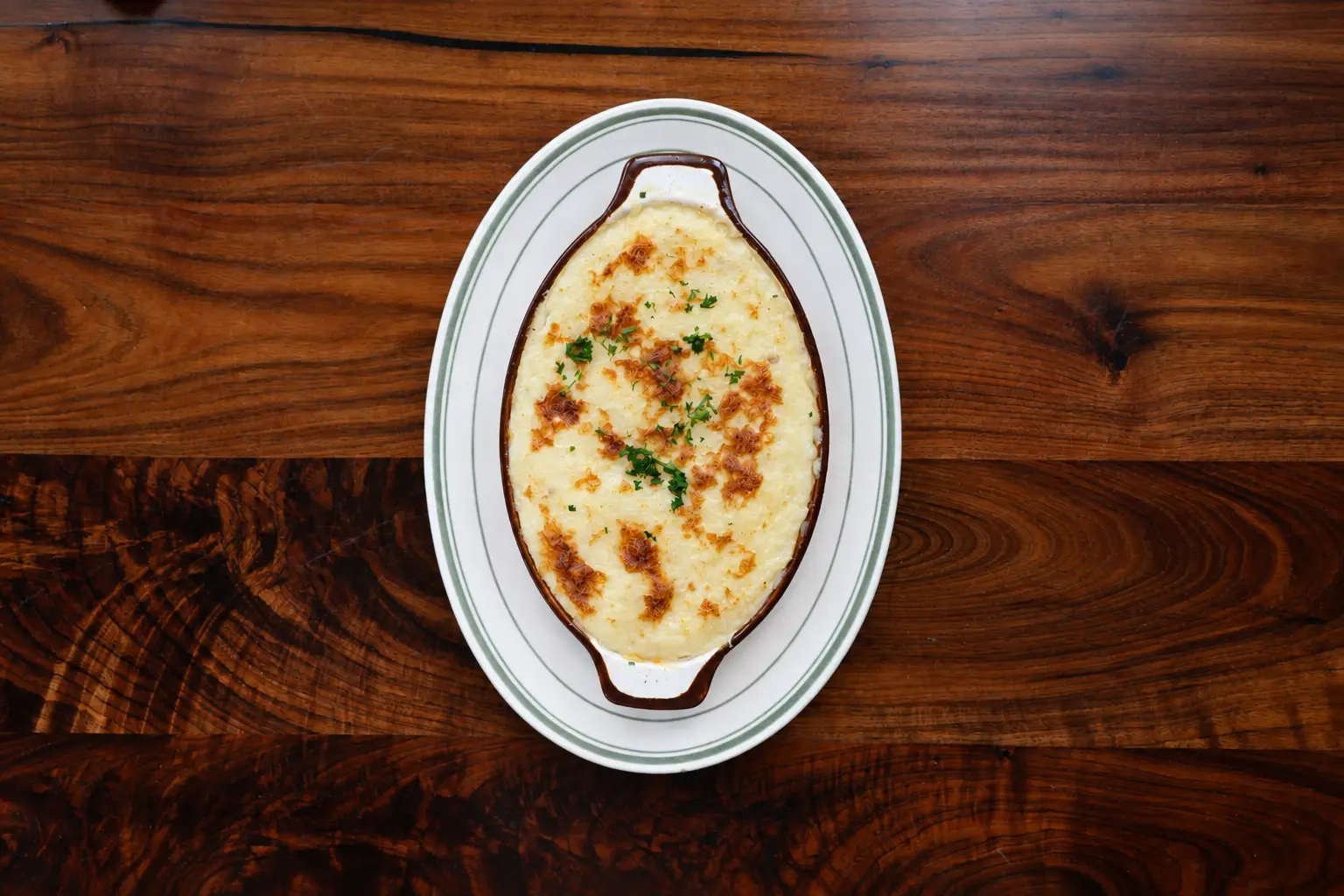 Shepherd's pie in an oval crock on a wooden table