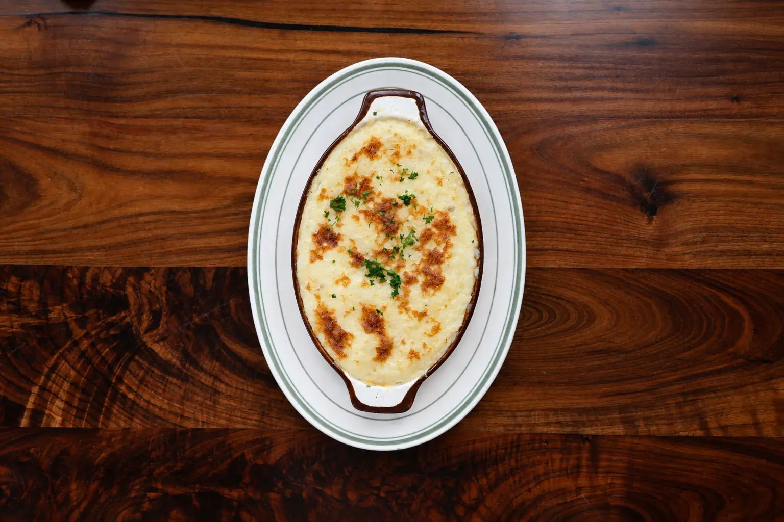Shepherd's pie in an oval crock on a wooden table